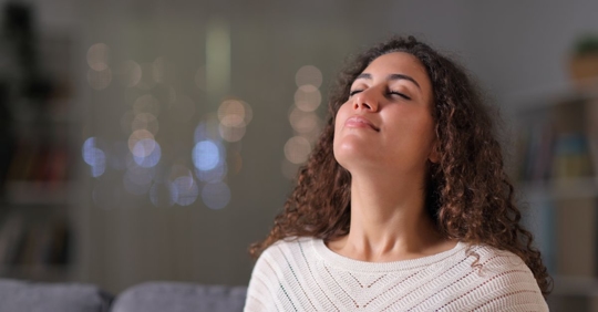 woman taking a deep breath at home